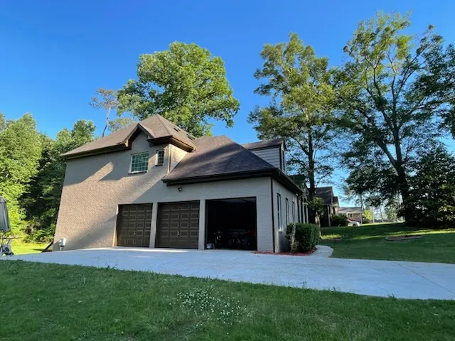 Brick home garage side after painting, with dark garage doors